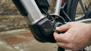 Close-up of an integrated ebike alarm and motion sensor unit with an active LED indicator and official UK security marking.