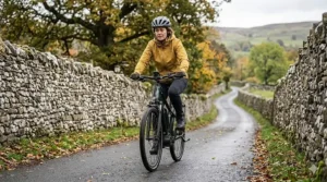 A cyclist using a torque sensor ebike to smoothly ascend a steep and narrow English country lane lined with traditional dry stone walls.