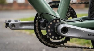 A close-up of a cadence sensor magnet ring and sensor unit mounted on an electric bike's crankset, showing the hardware used to detect pedalling speed.