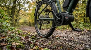 A close-up ground-level view of an ebike drivetrain on a damp autumnal bridleway covered in fallen leaves, showing the natural interaction of the pedals.