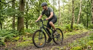 Alt text for image 9: A hardtail electric mountain bike being ridden on a light woodland trail in the UK countryside.