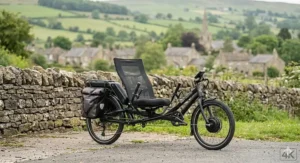 A three-wheeled electric recumbent trike parked on a flat surface, highlighting its stable design.