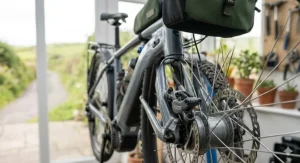 An ultra-detailed close-up of the front wheel assembly of the electric touring bicycle, focusing on the hydraulic disc brake caliper, rotor spokes, and high-traction, puncture-resistant tyre tread.