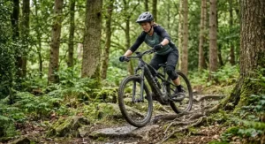 A mountain biker tackling a rugged woodland trail on a durable carbon fibre ebike.