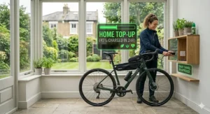 A cyclist in a home conservatory plugging their e-bike into a standard socket, with a digital overlay confirming a 2-hour charge top-up.
