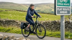 A happy cyclist riding an electric bike past a signpost indicating a flat cycle route ahead.