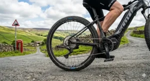 Rider on a mid-drive electric bike climbing a steep hill in the British countryside.
