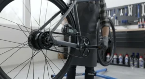 Professional cycle mechanic in a UK workshop checking the tension on an ebike carbon belt drive.