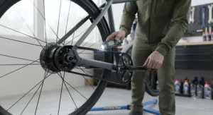 Cyclist washing down a modern commuter ebike with a low-pressure hose to keep the belt drive system clean.