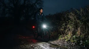 Bright integrated LED lights illuminating a road during a dark winter evening ride on a GPS-enabled commuter e-bike.