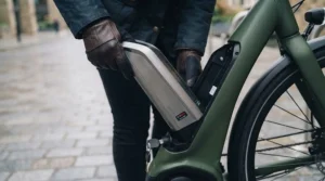 Commuter safely removing the secure, lockable battery from their electric bike outside a London office building.