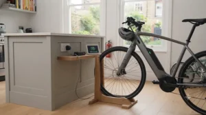 An e-bike safely charging indoors with a clear battery level display monitor nearby.
