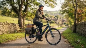 The rider, wearing a helmet, cycling the Volt e-bike along a paved path in the Cotswolds countryside.