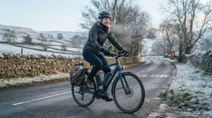 A rider cycling through a cold British winter landscape, showing a secondary battery fitted to help offset reduced capacity in low temperatures.