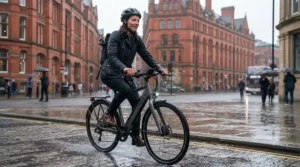A professional commuter riding an electric bike through a rainy Manchester city centre.