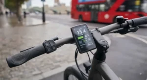 The handlebar LCD dashboard of a lit electric commuter bike showing speed and battery level in miles per hour.