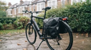A cyclist loading waterproof pannier bags onto the rear carrier rack of a practical utility electric bike.