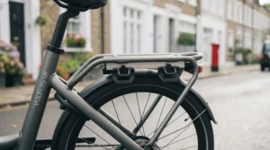 An all-weather electric bike with a weatherproof wrap-around backrest parked on a wet British pavement during a rainy afternoon.