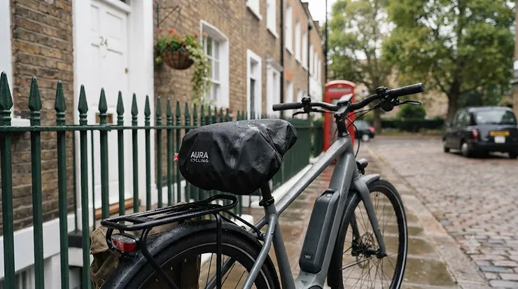 Black waterproof electric bike saddle cover fitted securely on an e-bike parked in a rainy British street. electric bike weatherproof saddle cover