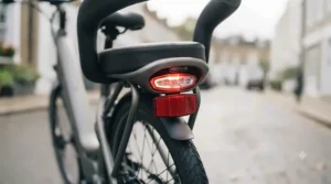 A compact folding electric bike fitted with a supportive wrap-around backrest, shown folded neatly in the boot of a car.